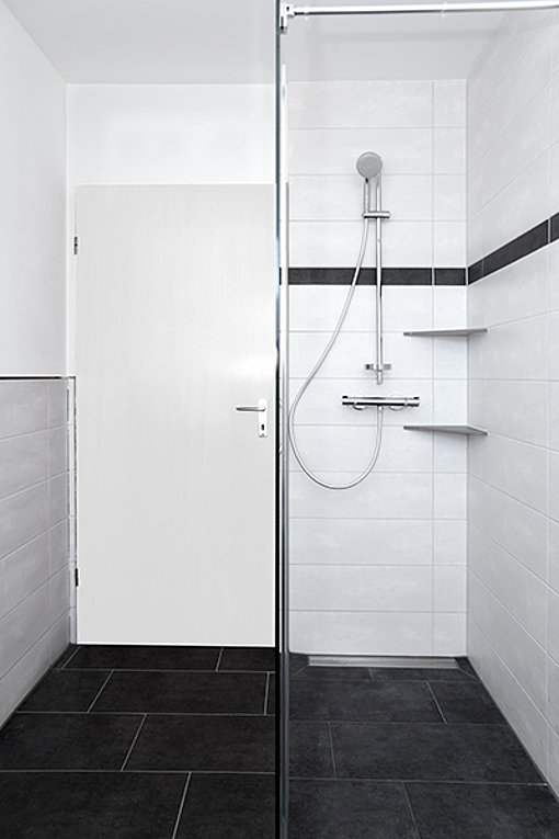 Auch eine bodentiefe Dusche findet im schwarz-weiß gehaltenen modernen Badezimmer Platz