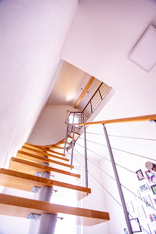 Eine moderne schicke Treppe aus Holz und Metall führt ins modernisierte Dachgeschoss