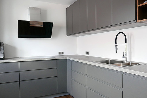 Nach der Modernisierung: Grifflose, graue Küchenschränke mit modernsten Geräten