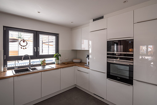 Nach der Modernisierung: Helle weiße Küche mit modernen Einbaugeräten. 